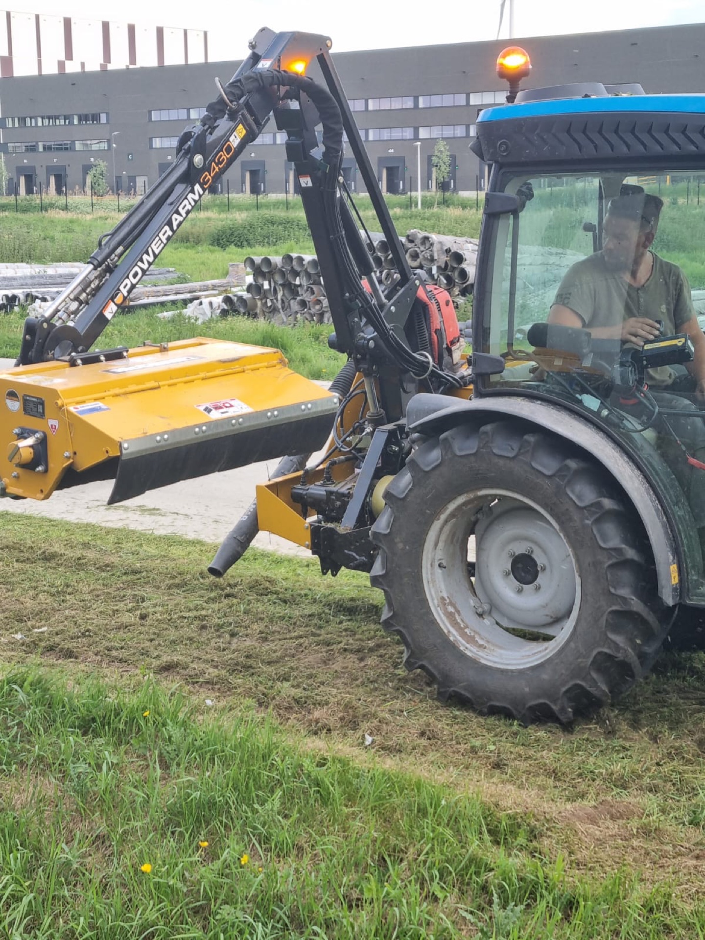 Achteraanzicht van de tractor met opgeklapte maaiarm