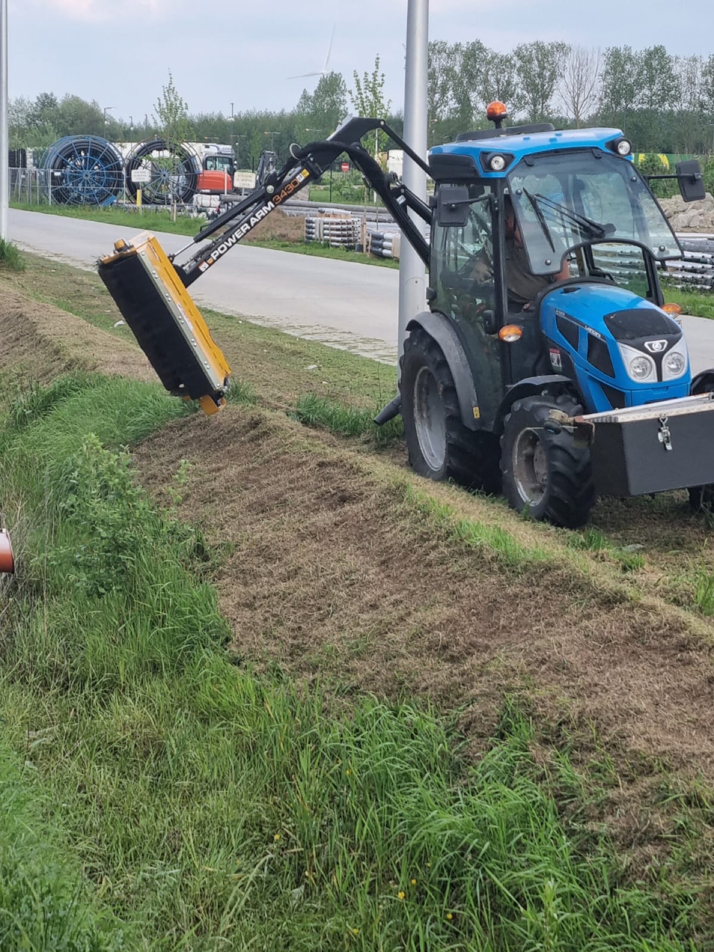 Maaiarm midden in de beweging op een grachtkant