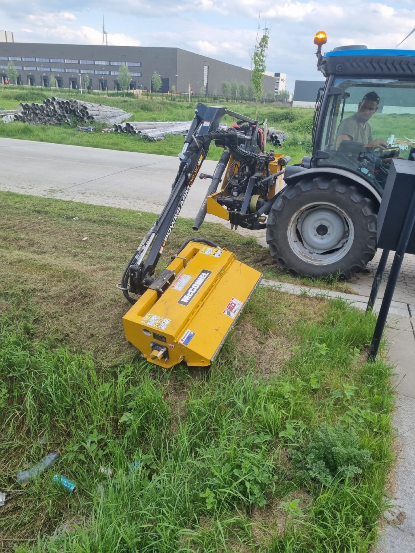 Maaiarm in werkpositie naast een industriële berm